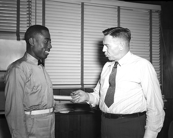 Hill receiving 10-year service pin from Woolman, 1945